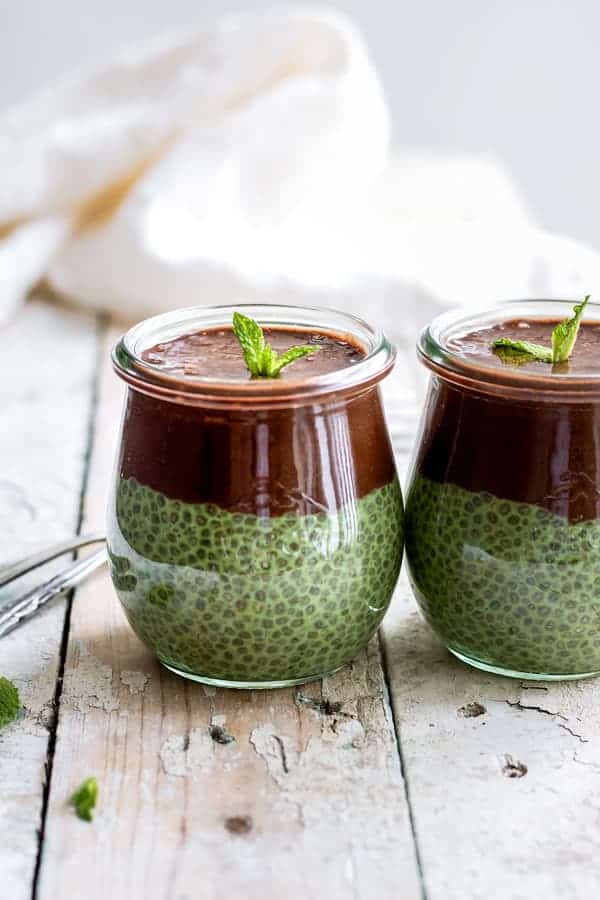 two jars of mint chia pudding topped with chocolate smoothie and mint leaves