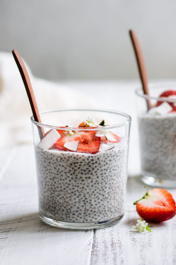 a cup of coconut chia pudding topped with strawberries and flaked coconut