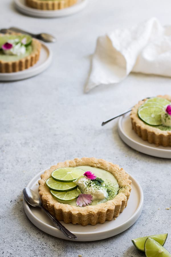 a mini vegan key lime pie on a white plate with a spoon on the side