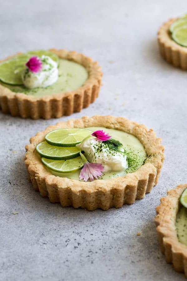 a mini key lime pie topped with sliced limes and whipped coconut cream