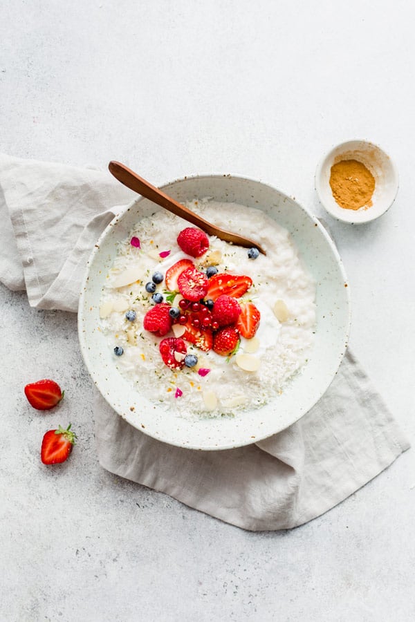 vegan coconut rice pudding made with coconut milk in bowl with spoon and berries