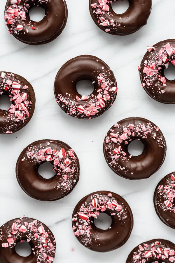 vegan peppermint mocha donuts on a marble board topped with crushed candy canes