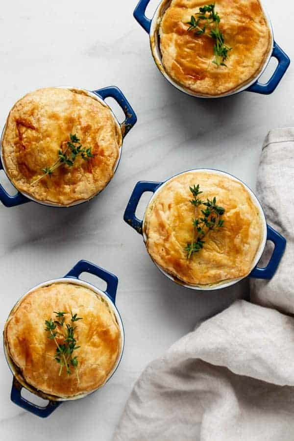 four veggie pot pies in blue ramekins topped with fresh thyme