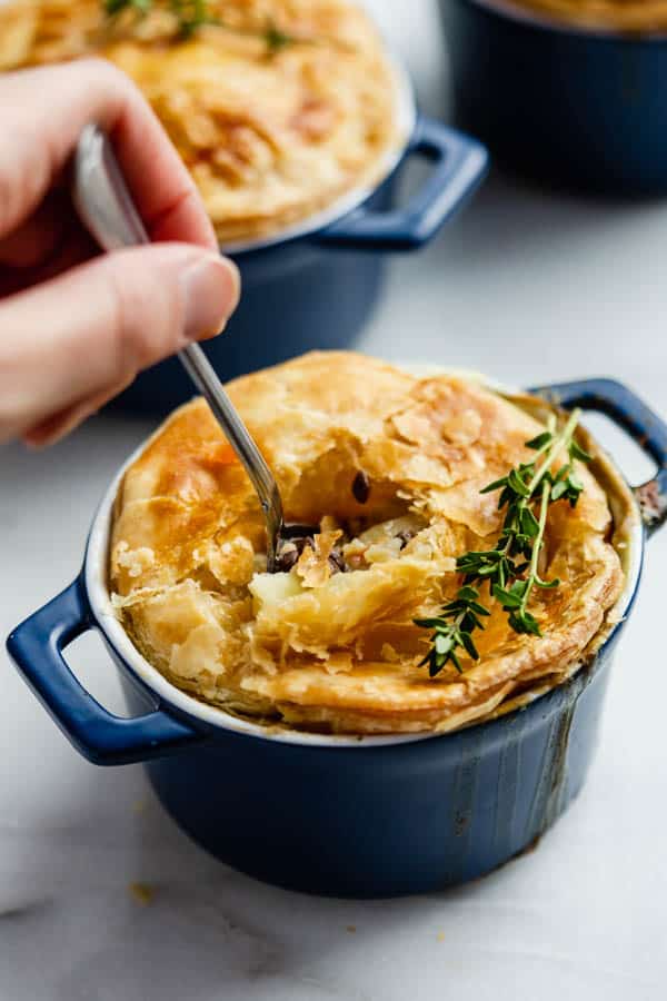 a spoon scooping a bite out of a mini veggie pot pie from a blue rakemin