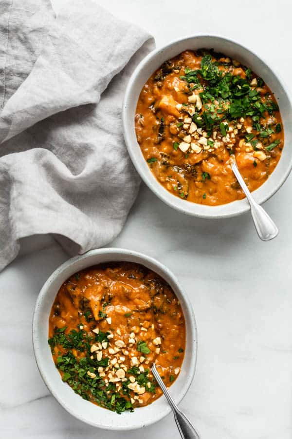 two bowls of west African peanut stew with a grey napkin next to them