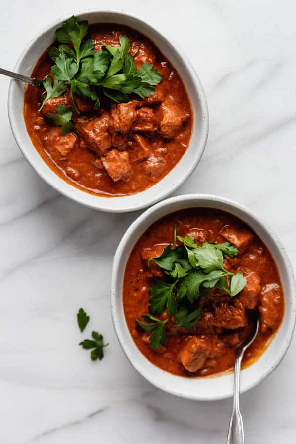 two oblong shaped bowls filled with tofu in a creamy tikka masala sauce 
