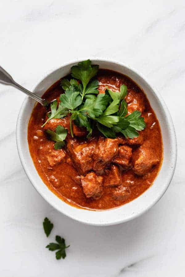 a bowl filled with tofu in a creamy red tikka masala sauce 