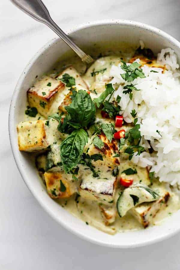 Thai green curry tofu in a bowl with basil, jasmine rice and chilli peppers