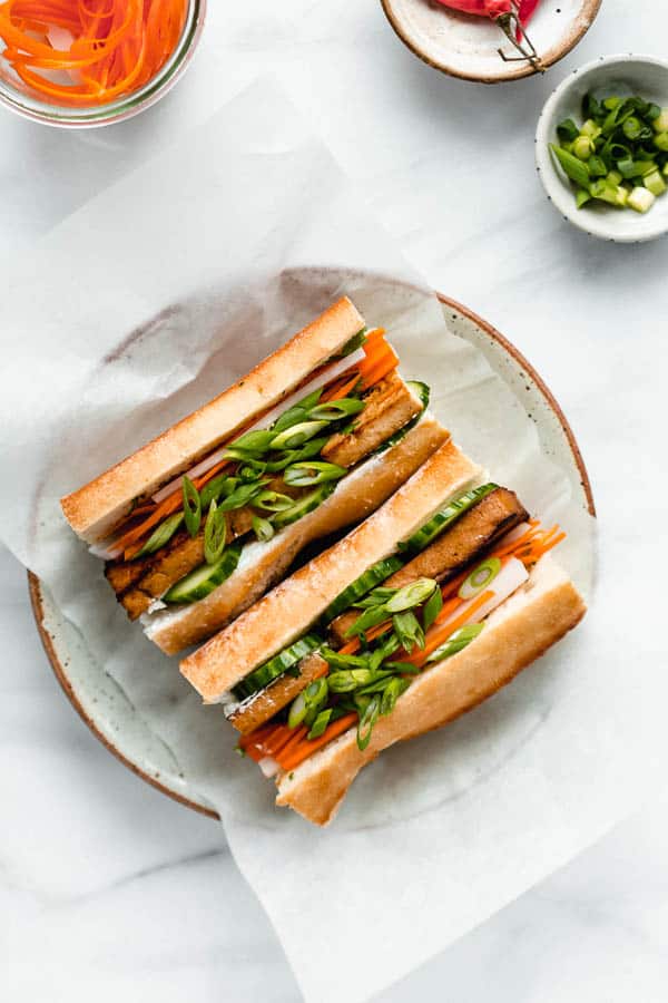 a plate with a tofu banh mi sandwich filled with pickled vegetables