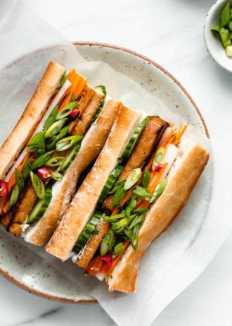 a plate with a tofu banh mi sandwich filled with pickled vegetables