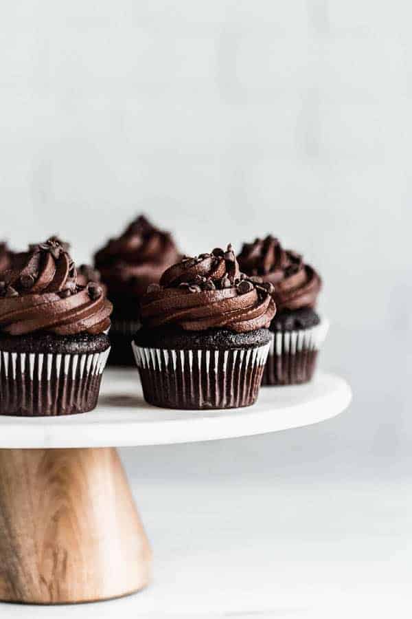 a marble cake stand with vegan chocolate cupcakes on it