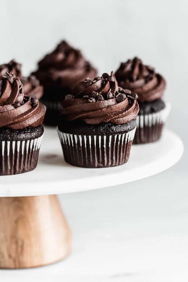 vegan chocolate cupcakes with chocolate frosting on a cake stand 