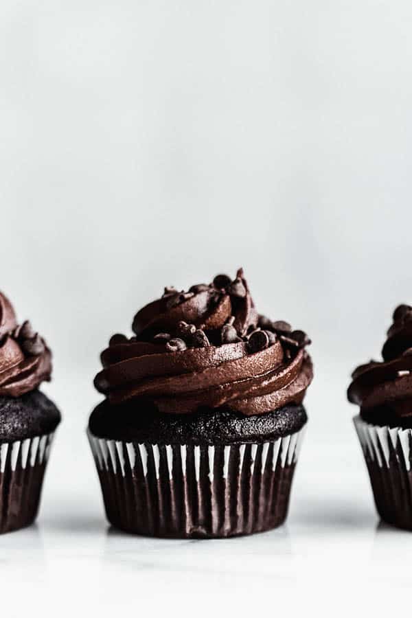 a vegan chocolate cupcake with chocolate icing and chocolate chips on top