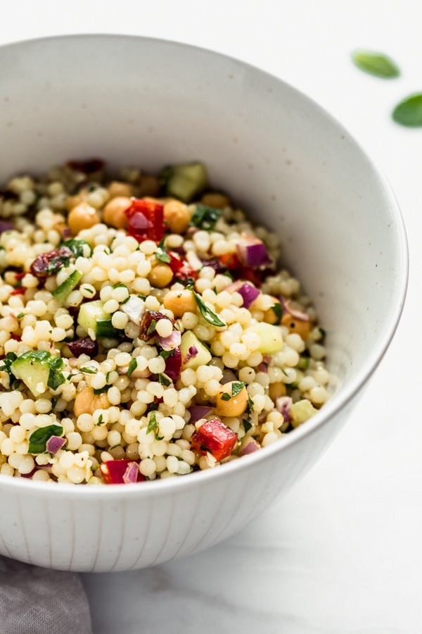 a close up shot of Israeli couscous salad with chickpeas and vegetables