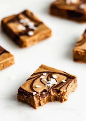 Salted almond butter fudge on a marble board with a bite taken out of it