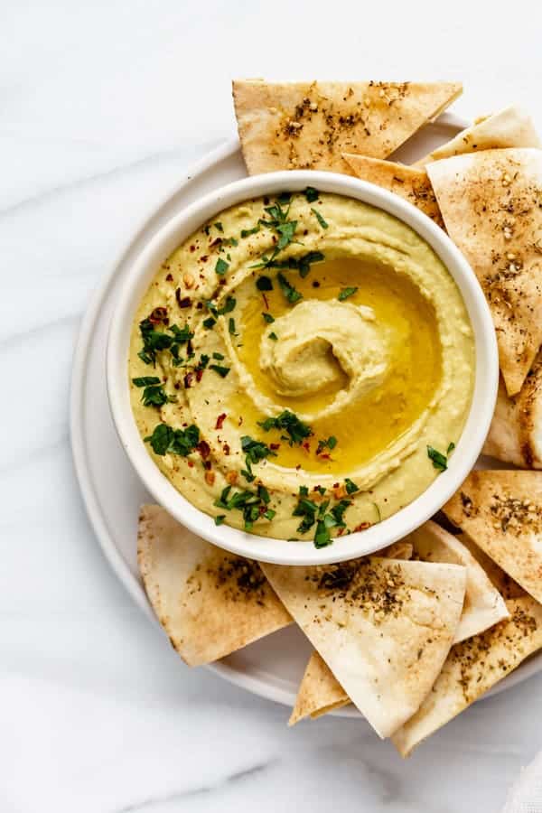 White bean dip in a dish with a side of pita chips 
