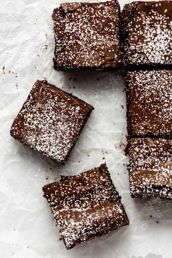 flourless fudge brownies cut into squares on some parchment paper 