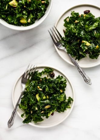 massaged kale salad recipe with avocado and cranberries on 2 plates