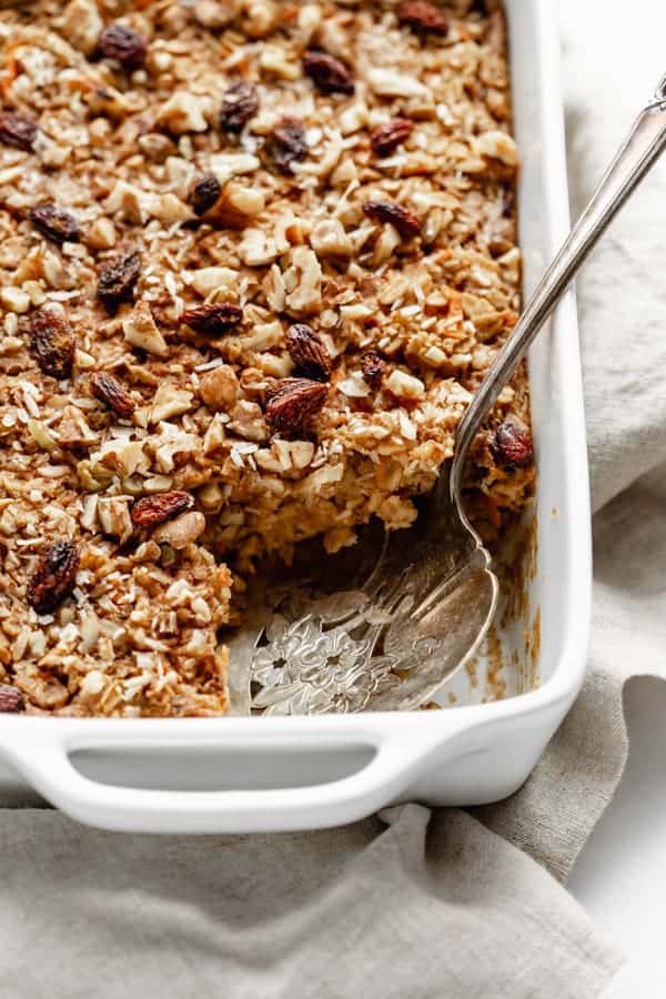 a close up of carrot cake baked oatmeal with a serving spoon 