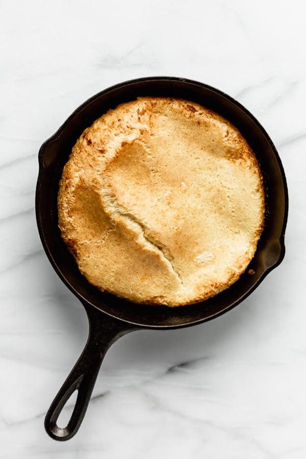 a cooked puffy dutch baby in a cast iron skillet