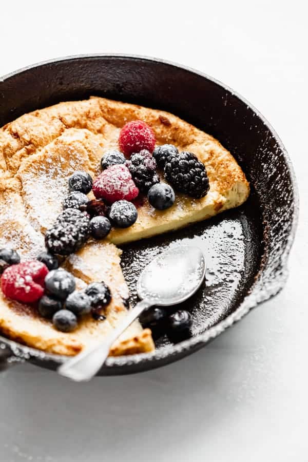 Close up of a dutch baby pancake in a skillet with a spoon 