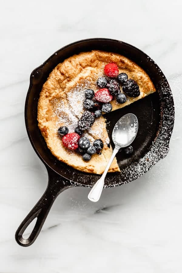 a dutch baby pancake in a pan with a spoon and berries 