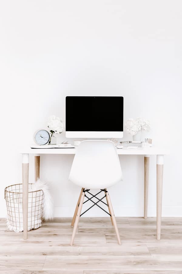 a white desk with wooden legs with an imac and a chair