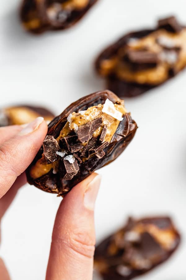 two fingers holding a date stuffed with almond butter
