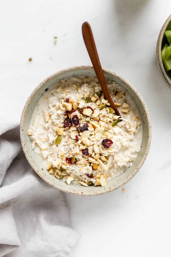 a bowl of bircher muesli topped with chopped cashews, dried cranberries and coconut
