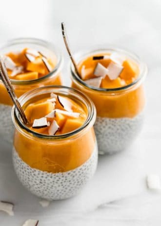 3 jars filled with coconut chia pudding and mango puree