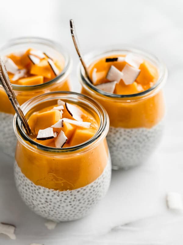 3 jars filled with coconut chia pudding and mango puree