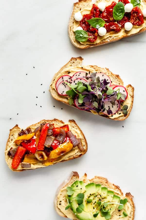 4 pieces of hummus on toast with toppings