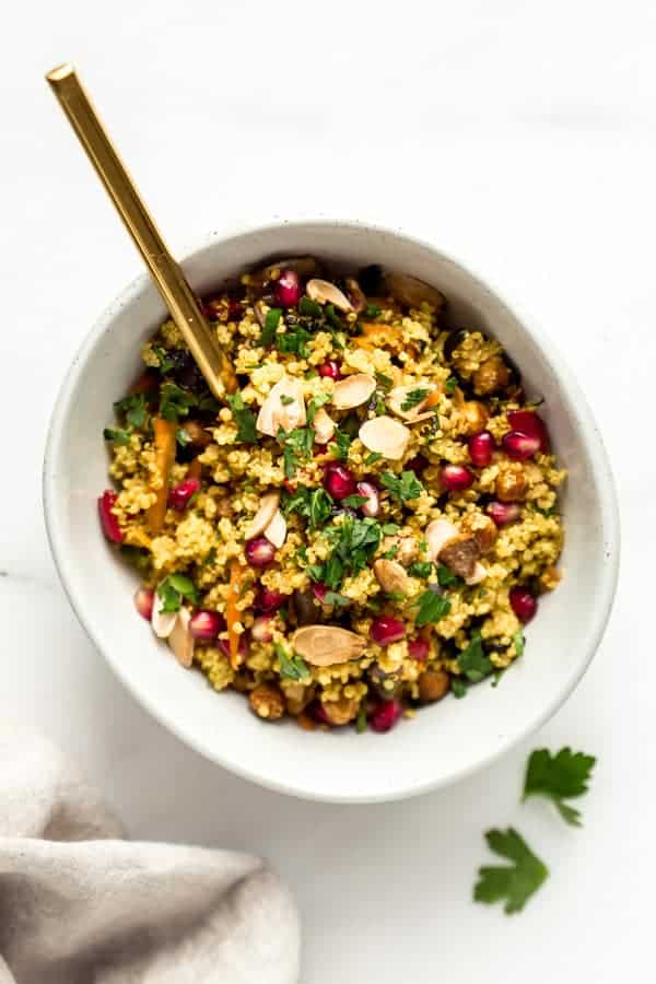 A bowl with Moroccan quinoa salad and a gold spoon