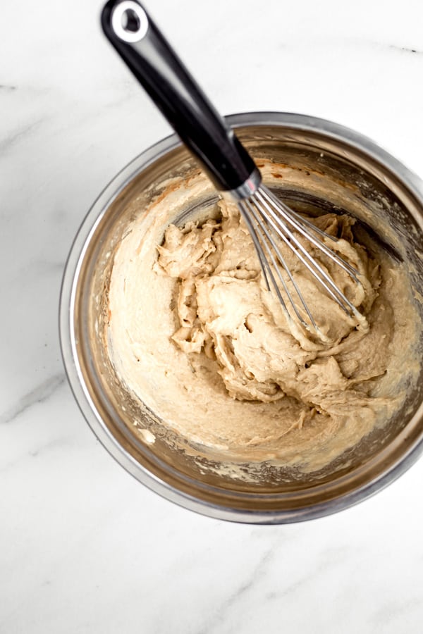 a bowl with a tahini and egg mixture with a whisk in it