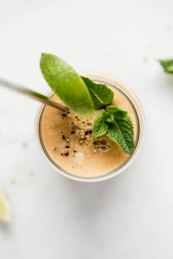 a top down view of a papaya smoothie with a lime wedge and mint