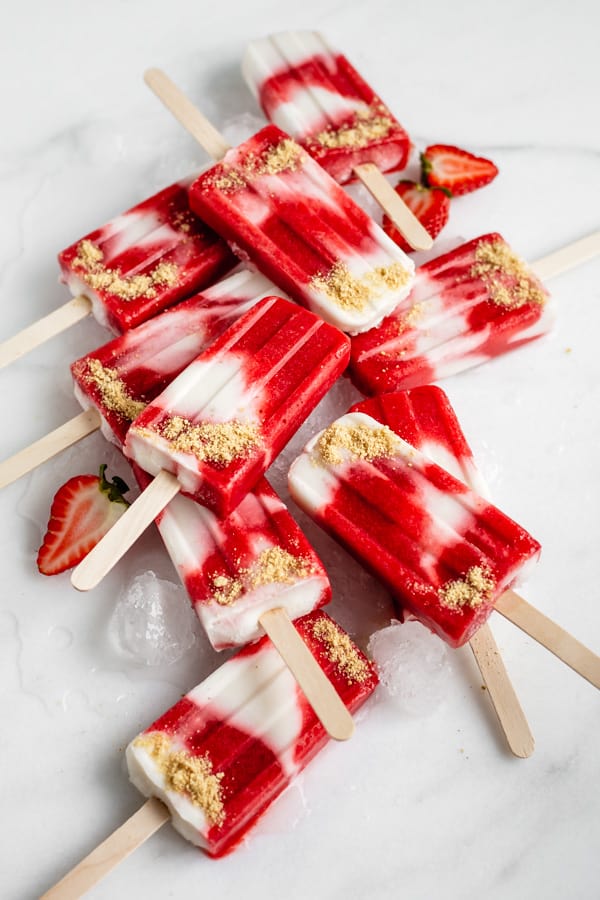 vegan strawberry cheesecake popsicles stacked one on top of the other