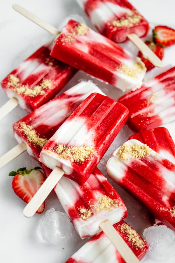 strawberry cheesecale popsicles stacked on ice
