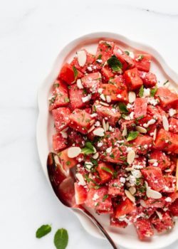 a platter with watermelon feta salad topped with mint and almonds
