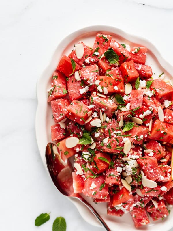 a platter with watermelon feta salad topped with mint and almonds