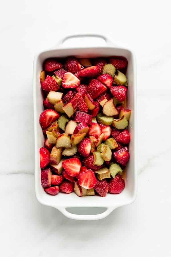 a white baking dish filled with strawberries and rhubarb