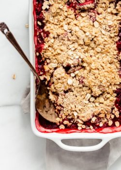 strawberry rhubarb crisp in a baking dish with a spoon in it