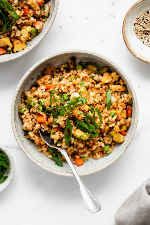 vegan fried rice in a bowl with a side of sesame seeds