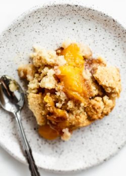 gluten-free peach cobbler on a white speckled plate