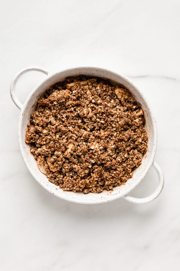 a baked apple crisp in a round white baking dish