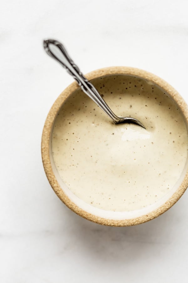 a small ceramic bowl with creamy vegan Caesar dressing in it