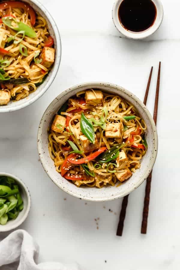 Singapore noodles in a speckeld ceramic bowl with wooden chopsticks on the sie