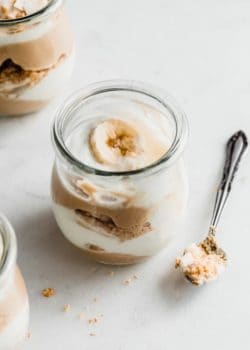 a cup of vegan banana cream pie parfait with a spoon next to it
