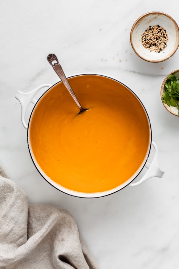 Butternut squash soup in a white pot with a serving spoon