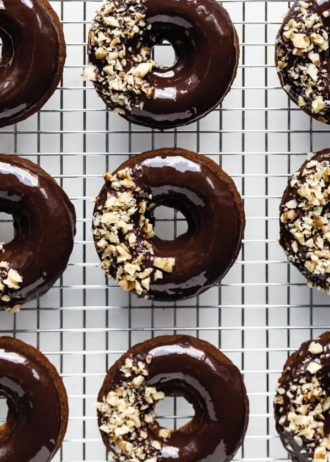 nine donuts topped with chocolate glaze on a silver cooling rack