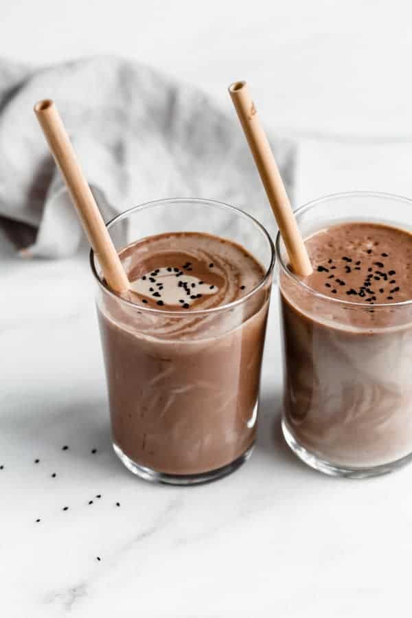 two glasses of chocolate tahini smoothies on a marble counter